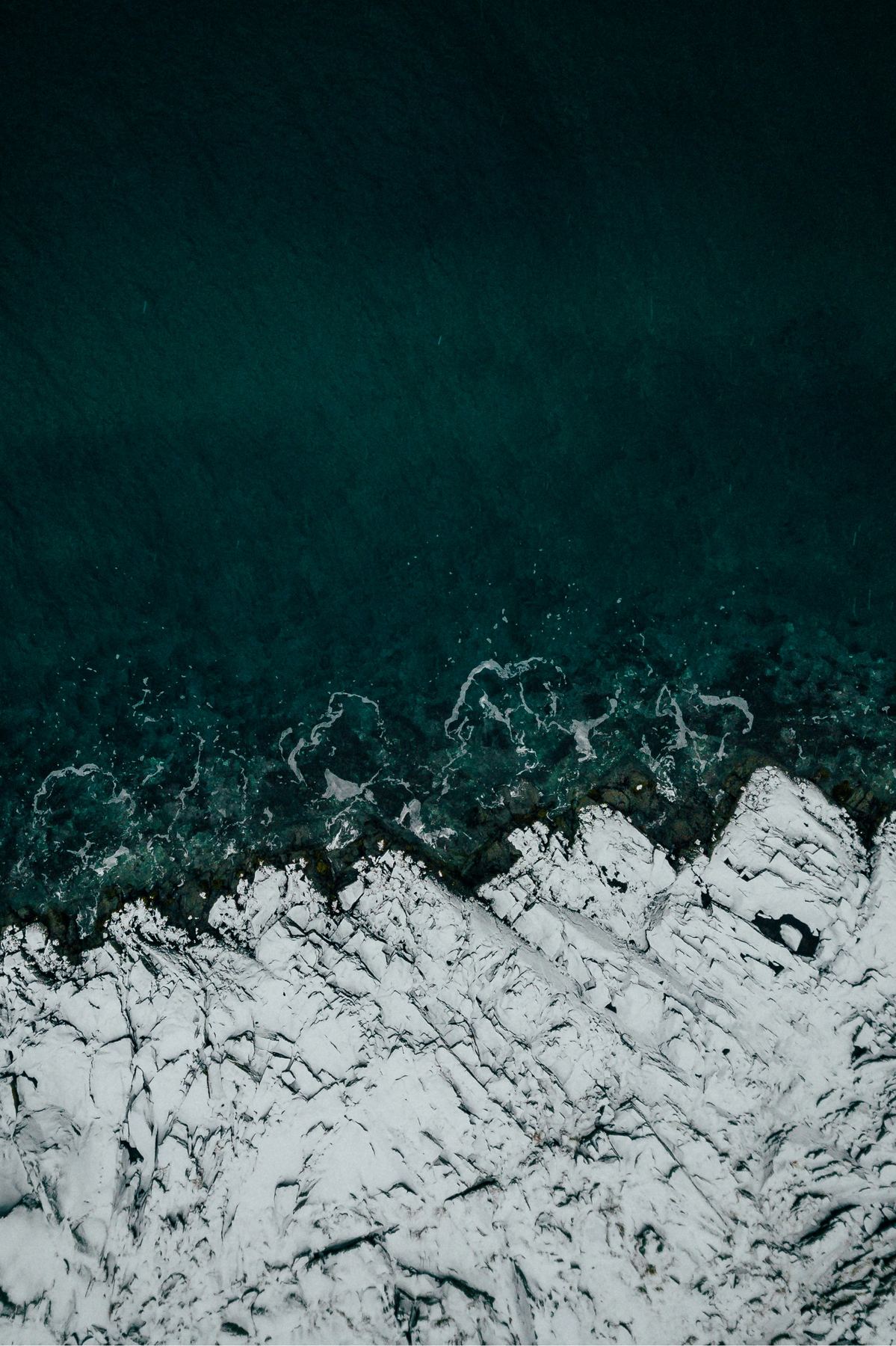 Quiet coastline seen from above in muted teal and stone tones